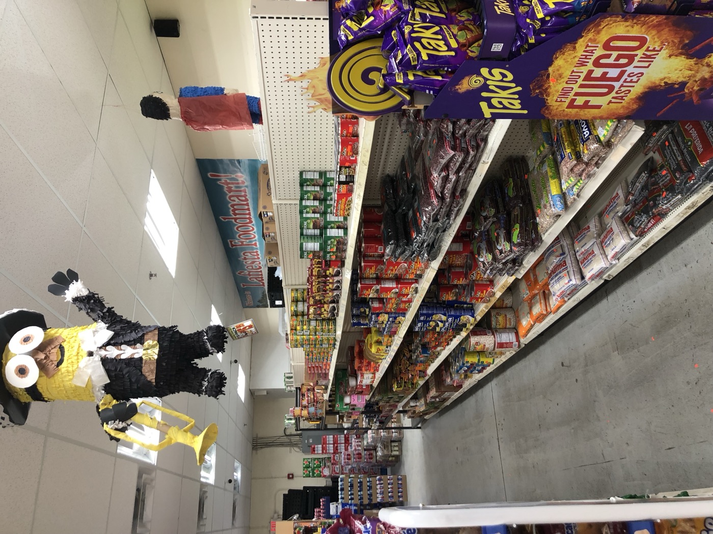 Inside La Fiesta Food Mart, grocery aisles with the store sign in the background
